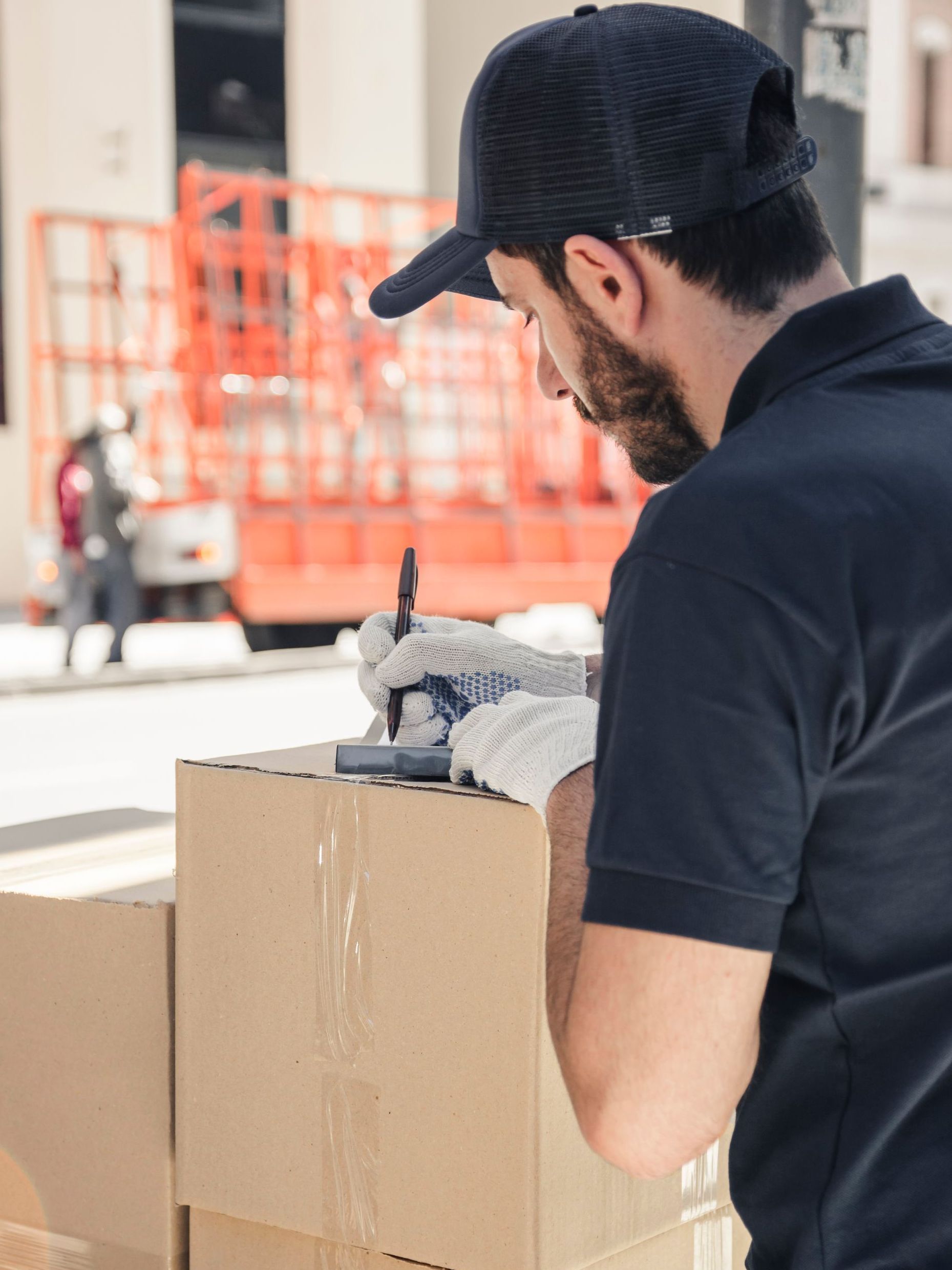 A delivery man is writing on a cardboard box.