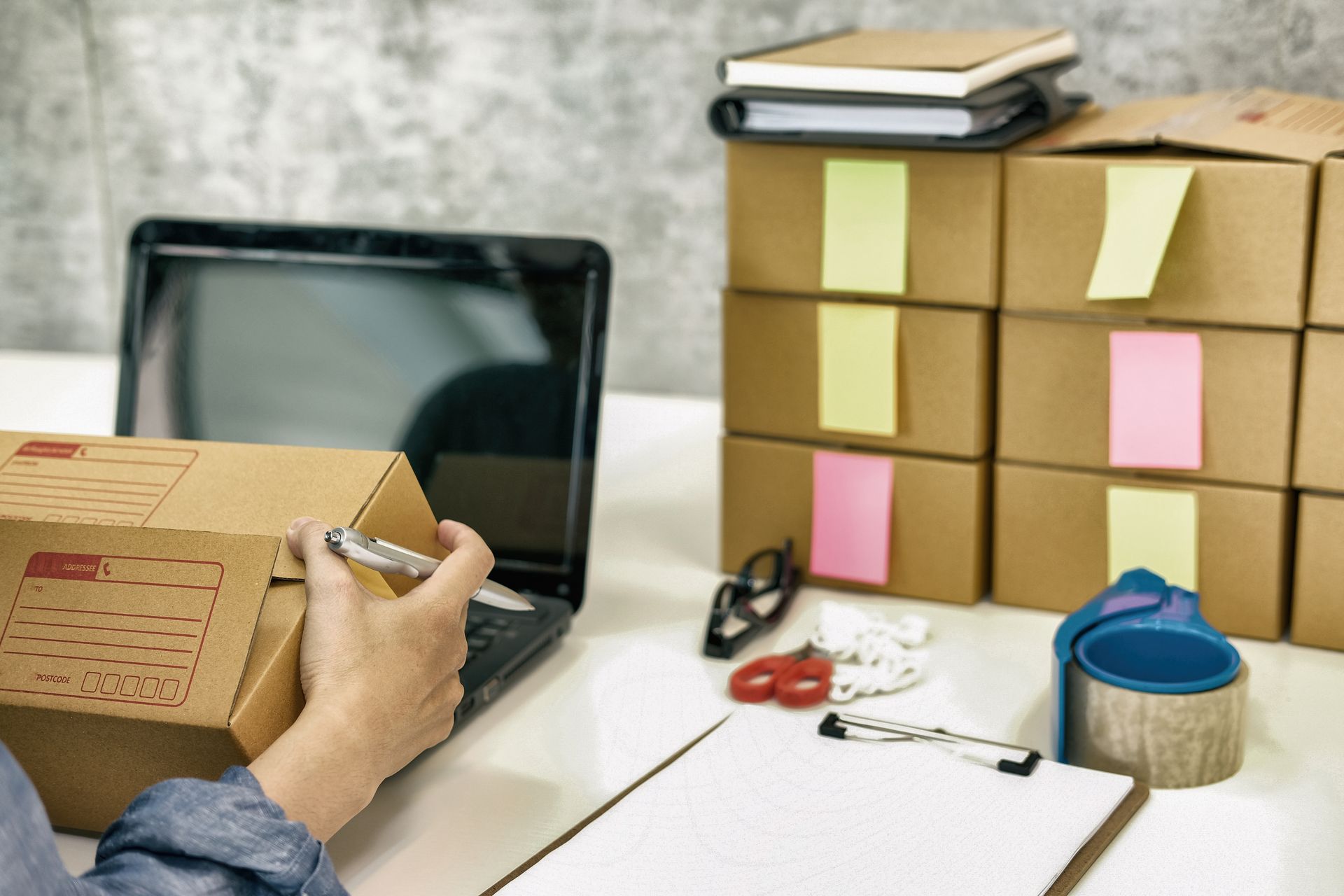 A person is holding a box in front of a laptop computer.