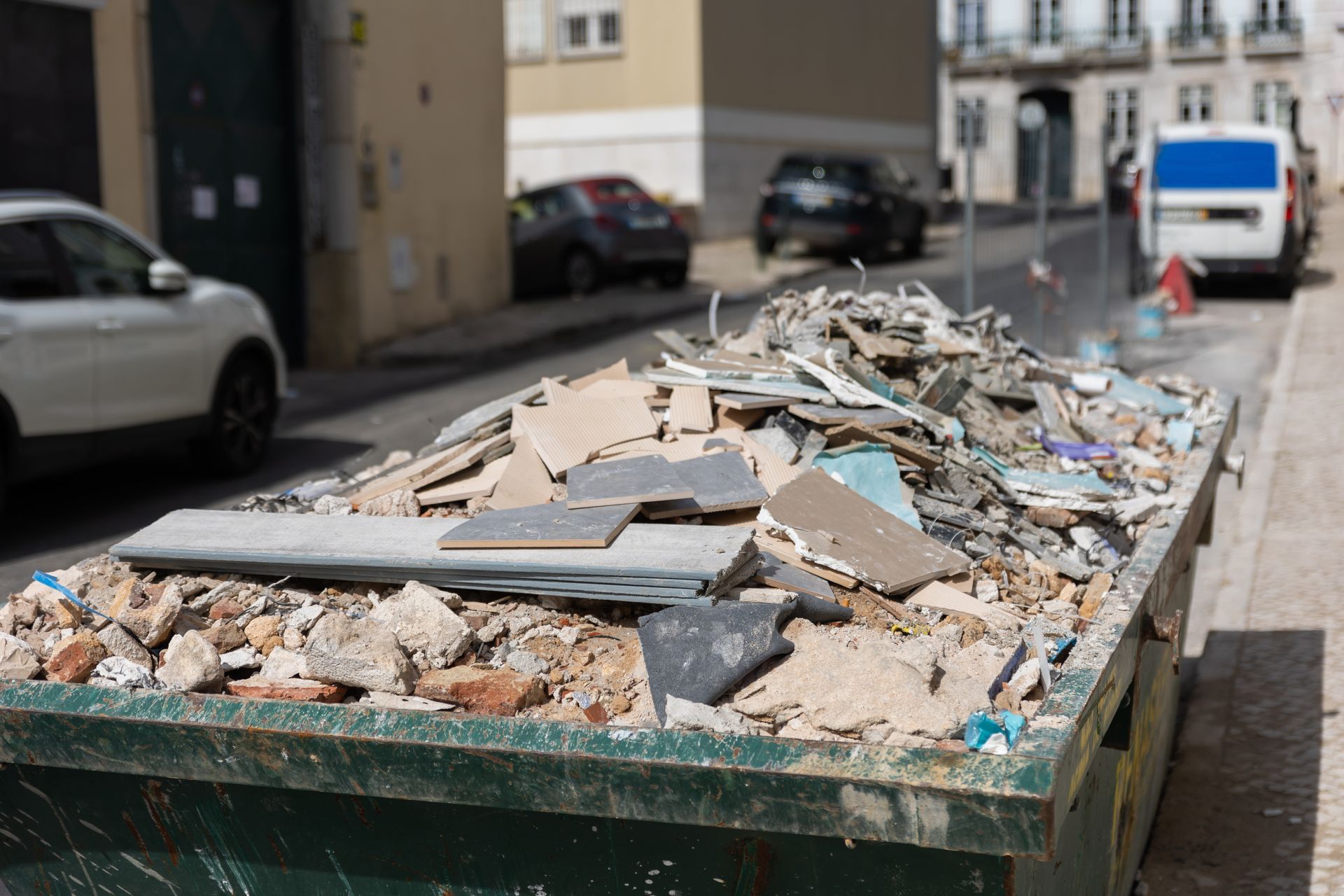 A dumpster filled with construction debris on the side of a street.