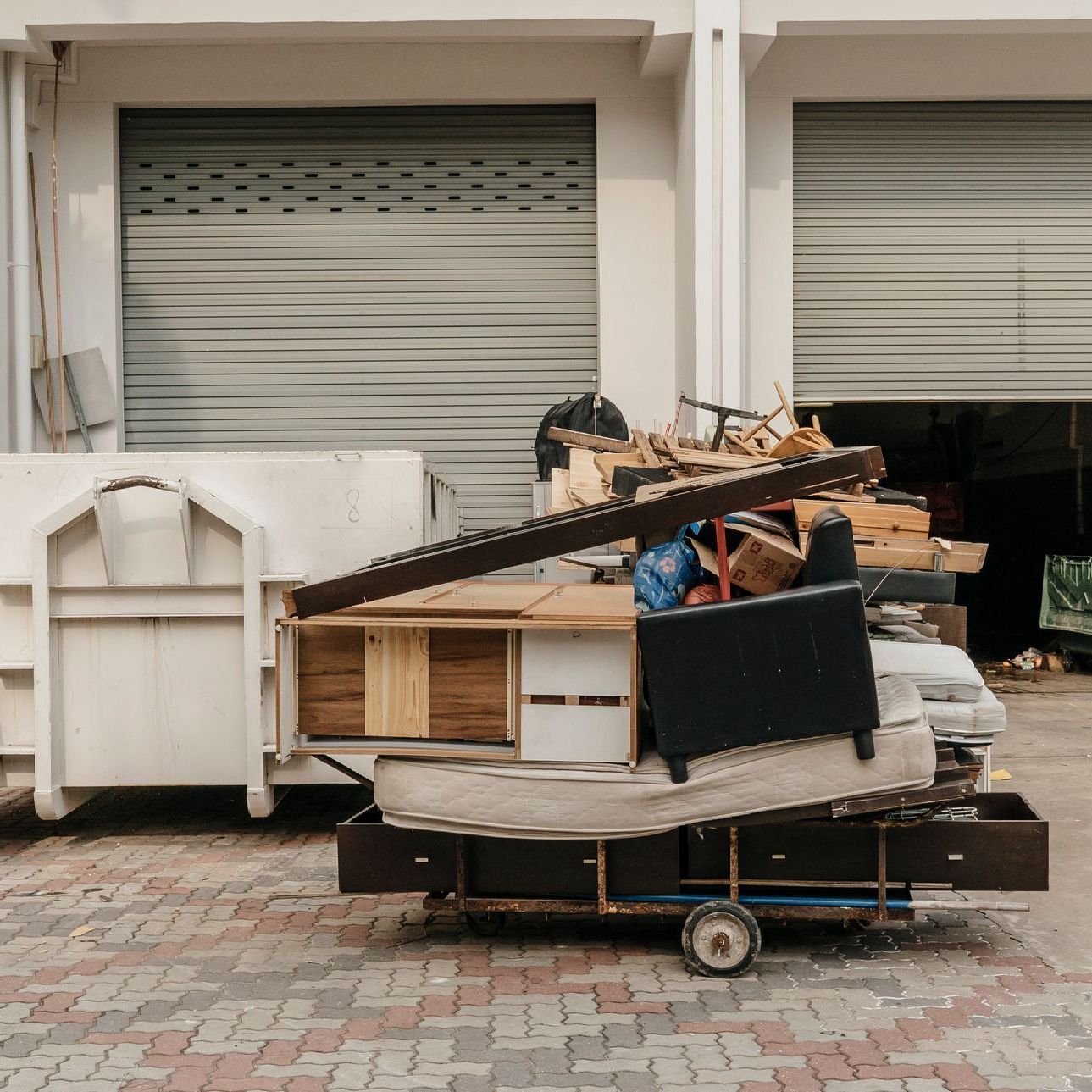 A cart filled with furniture is parked in front of a garage door.