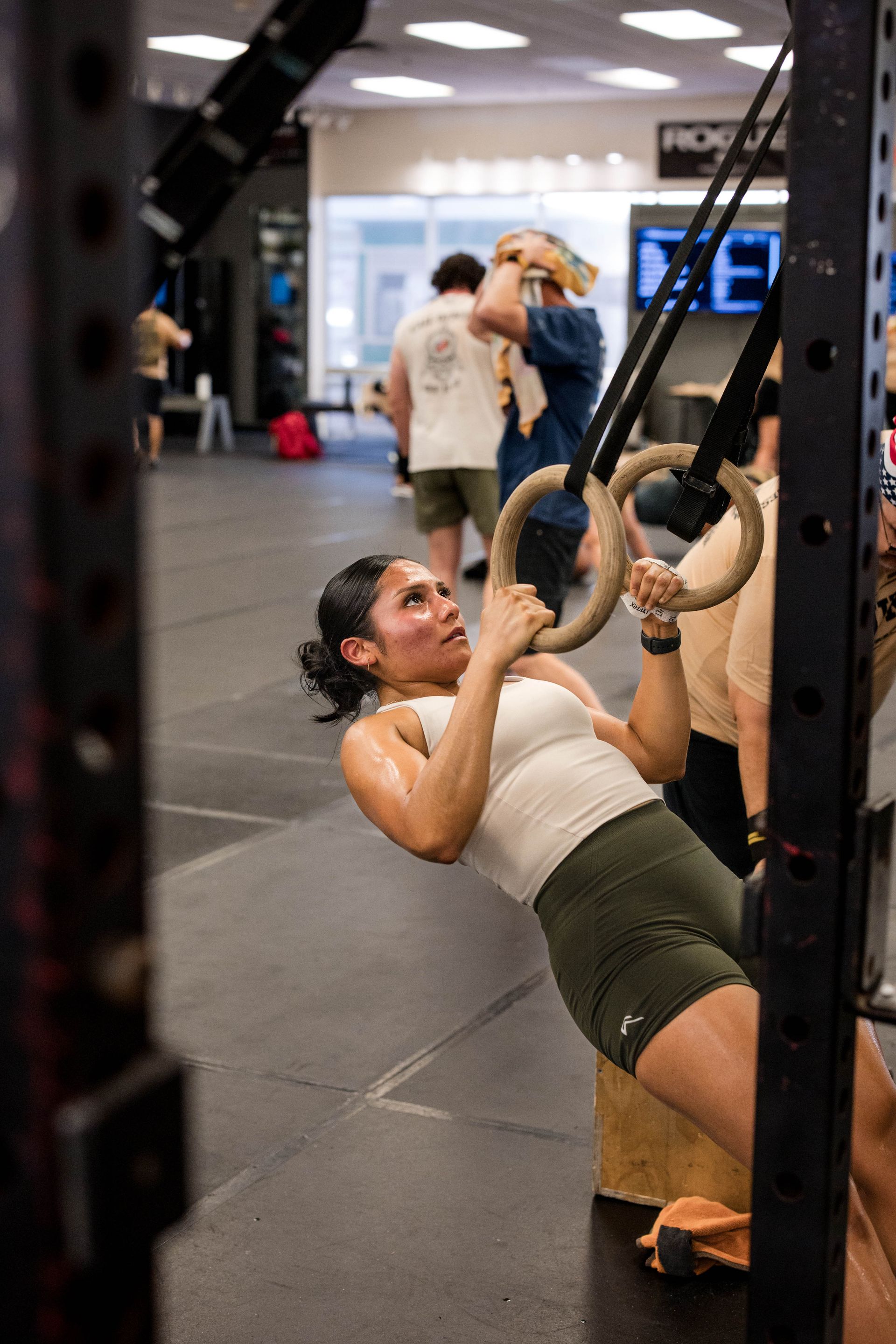 A man is doing dips with a trainer in a gym.