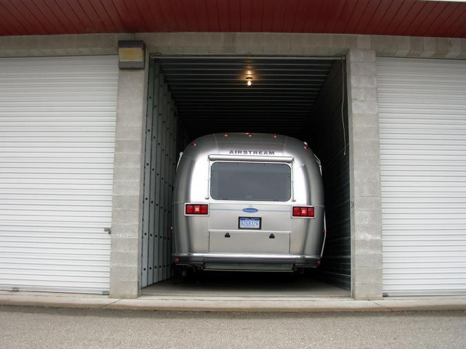 A silver airstream is parked in a garage