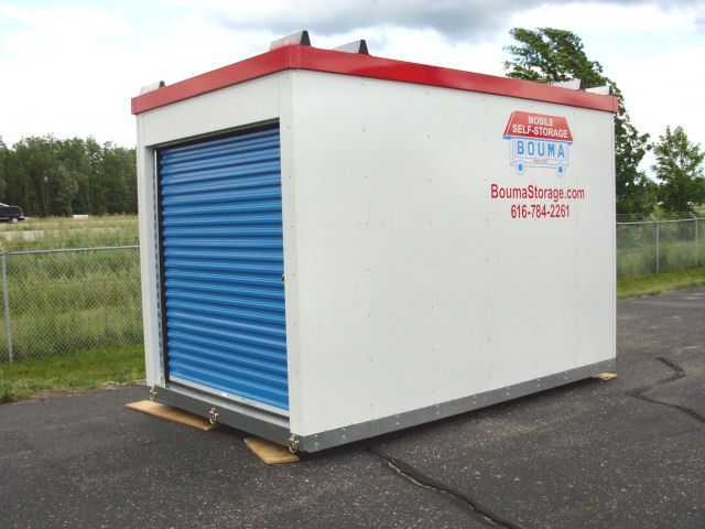 A small white building with a blue door and a red roof