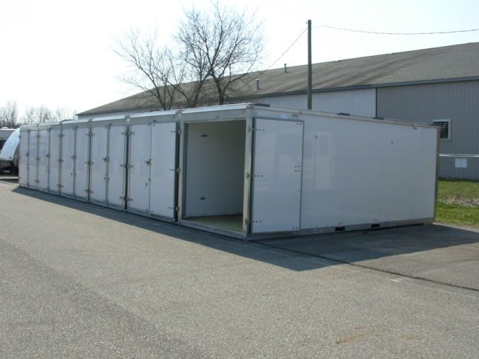 A row of white containers are lined up on the side of the road