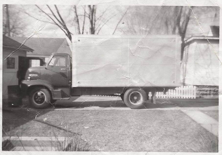 A black and white photo of a truck parked on the side of the road.