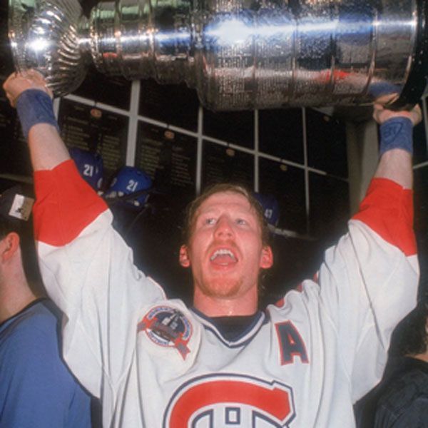 Hockey player, Montreal Canadiens, holding up the Stanley Cup trophy, arms raised in celebration.