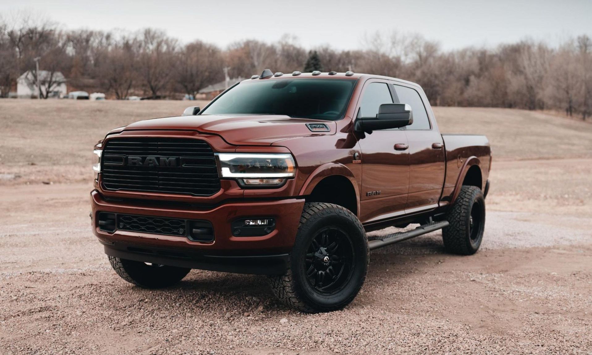 A red ram truck is parked in a dirt field.