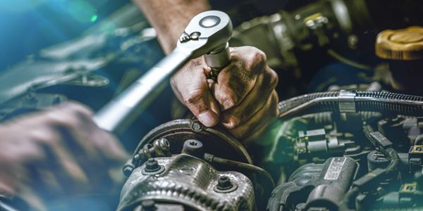 A man is working on a car engine with a wrench.