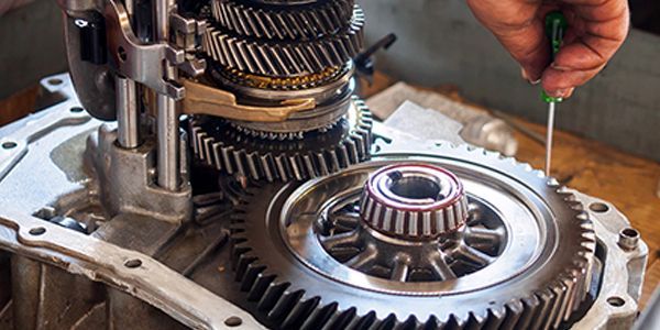 A person is working on a gearbox with a screwdriver.