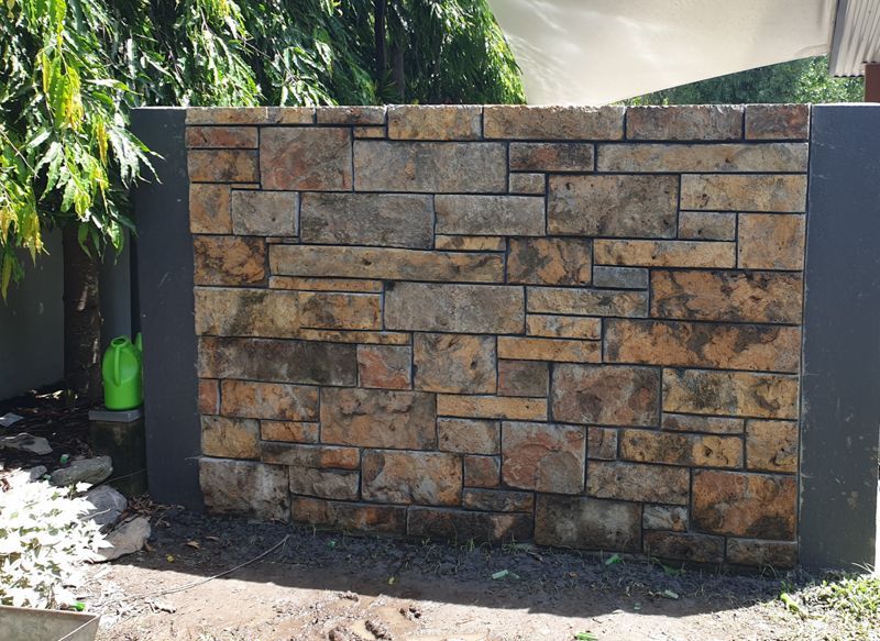 A brick wall with a green watering can in front of it.