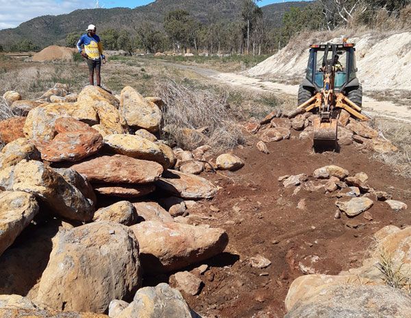 A man standing on a pile of rocks next to a tractor