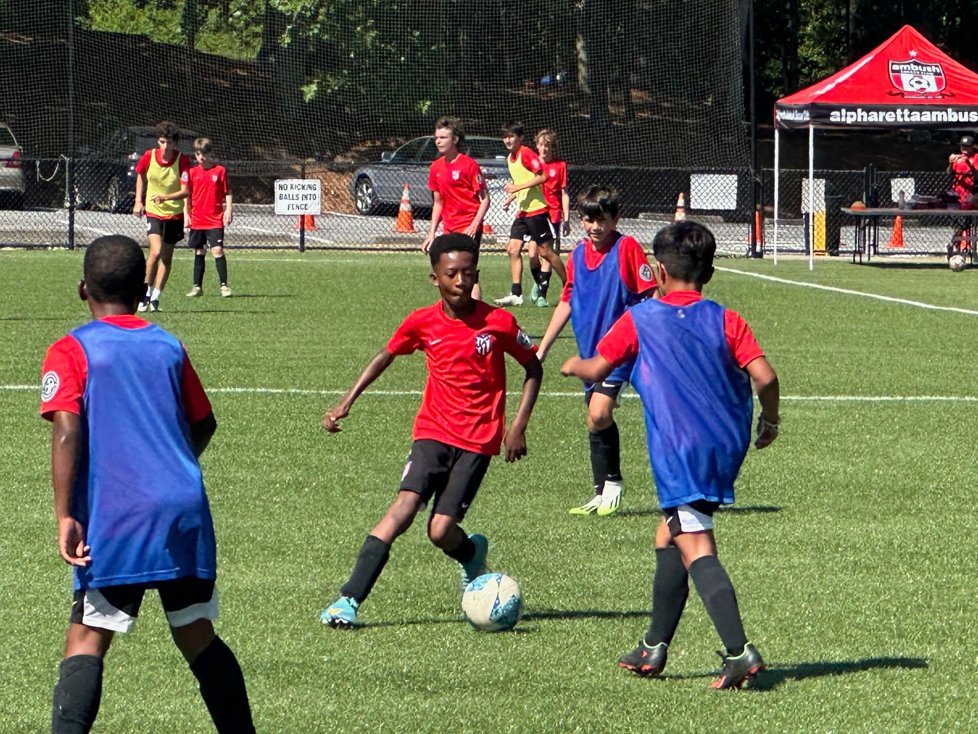 A group of Alpharetta Ambush Soccer Club's young boys are playing soccer on a field.