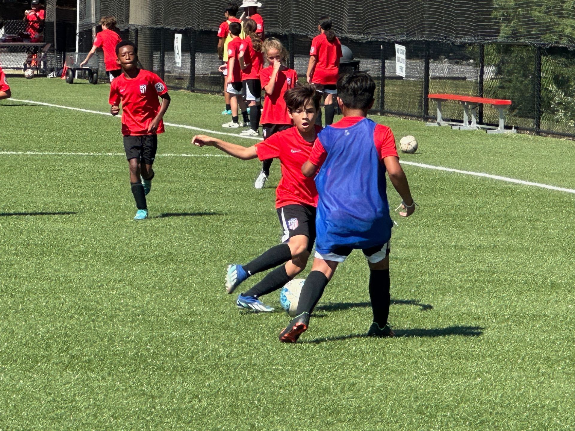 A group of Alpharetta Ambush Soccer Club's young boys are playing soccer on a field.