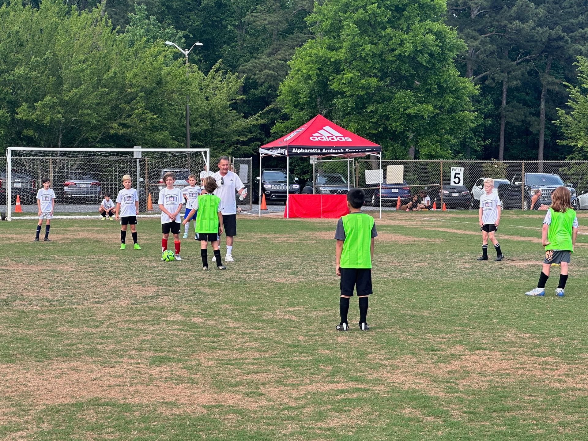 A group of Alpharetta Ambush Soccer Club's young boys are playing soccer on a field.