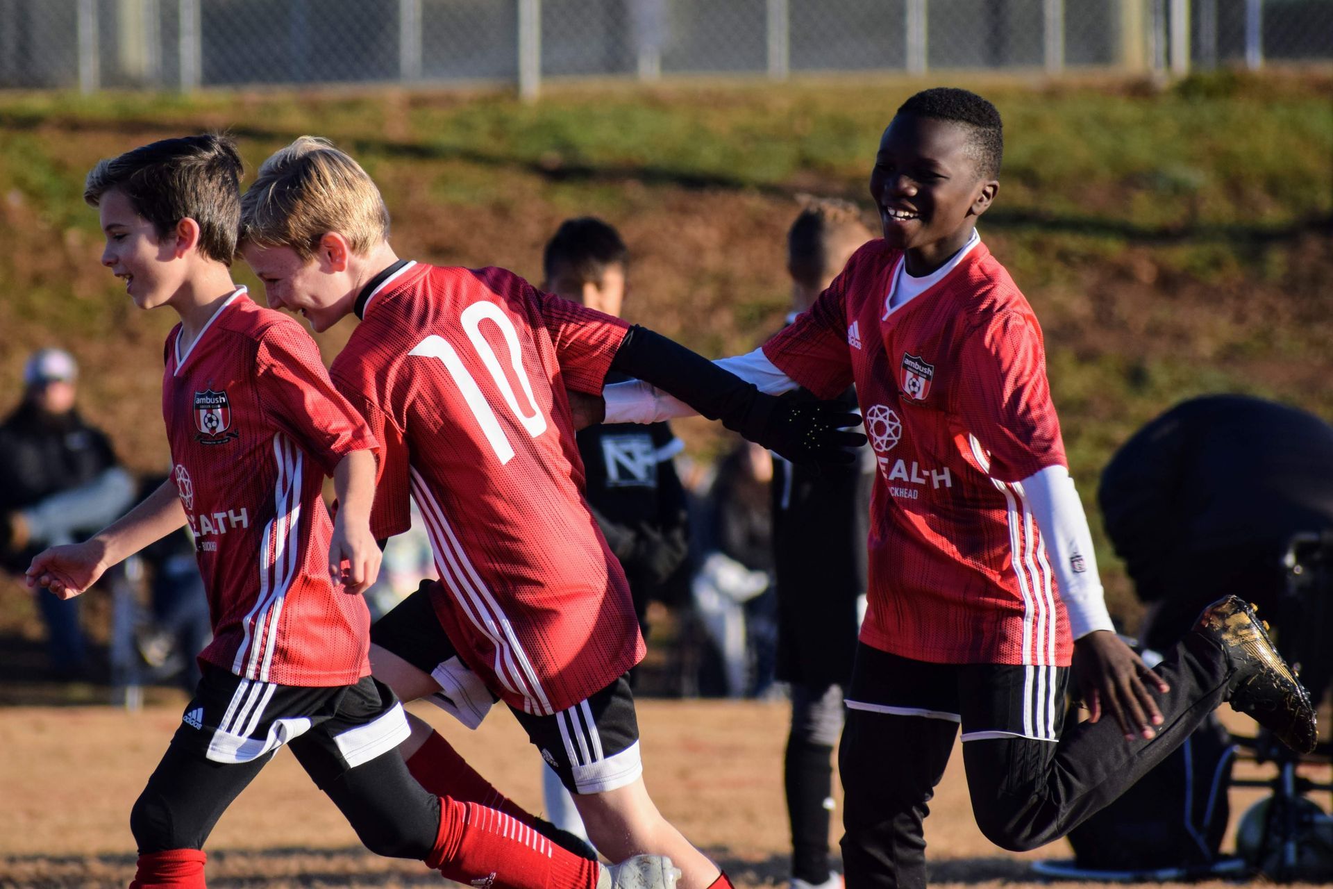 A group of Alpharetta Ambush Soccer Club boys playing soccer on a field.