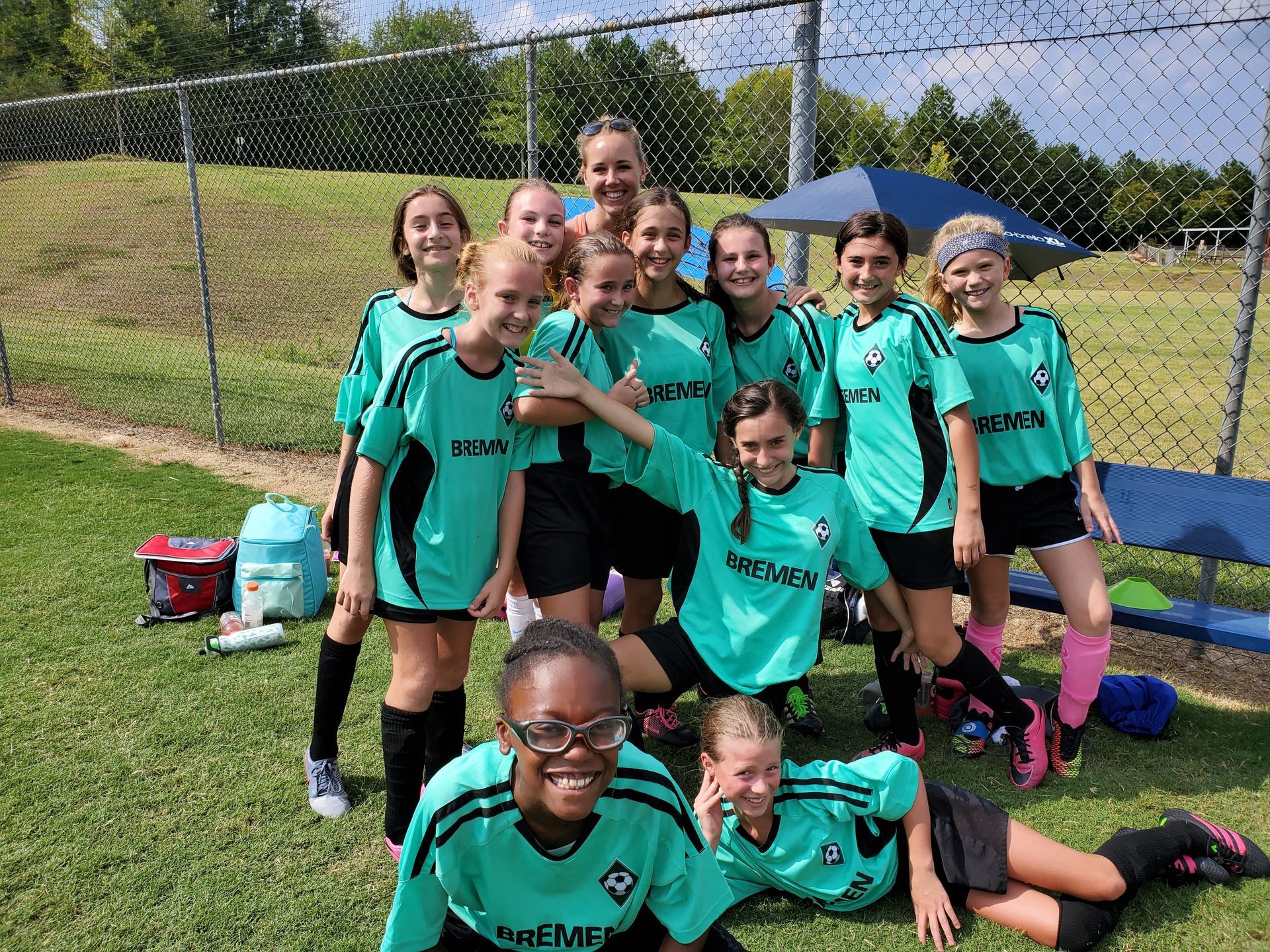 A group of Alpharetta Ambush Soccer Clubs young girls are posing for a picture on a field.