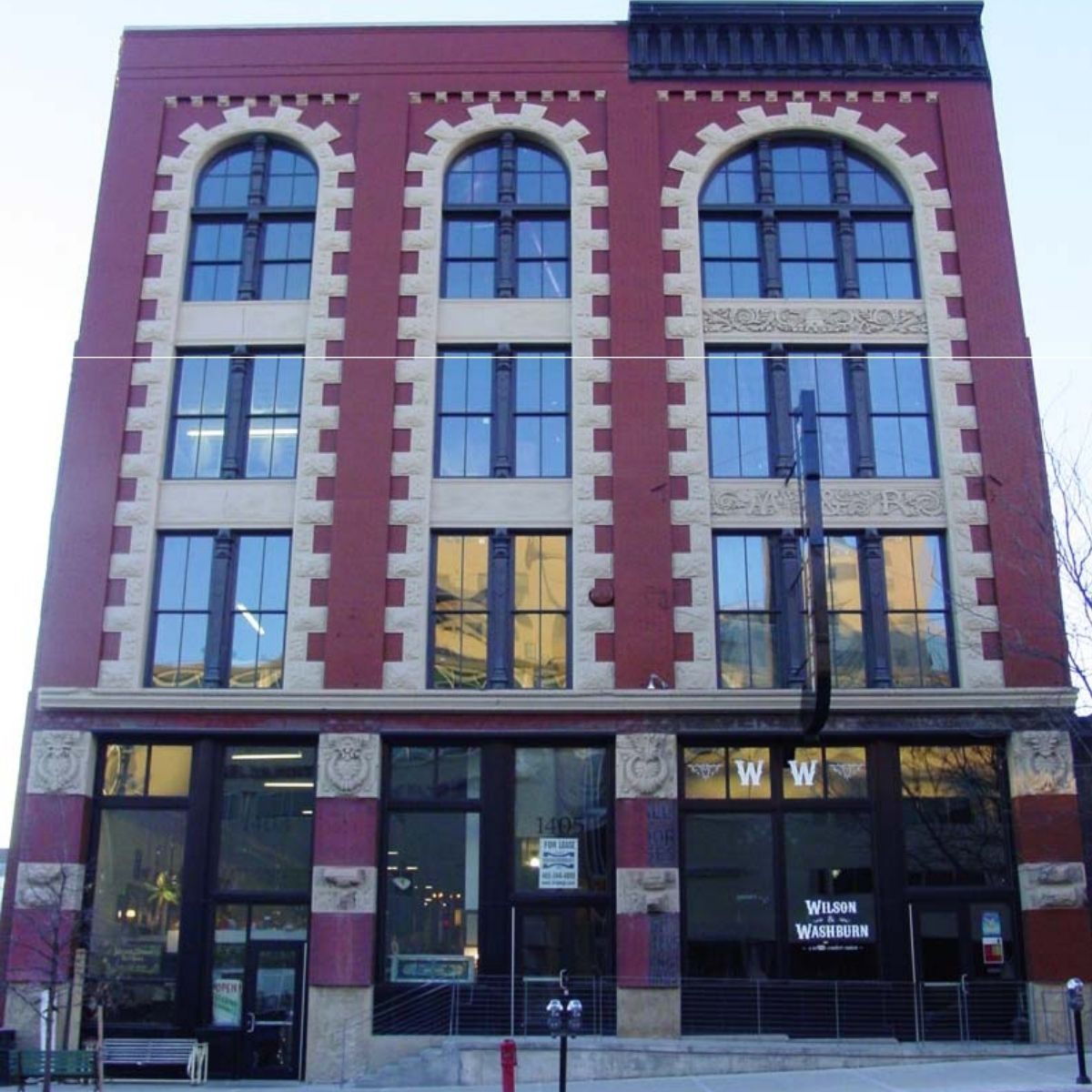 Historic four-story brick building with tall arched windows and ground-floor storefronts