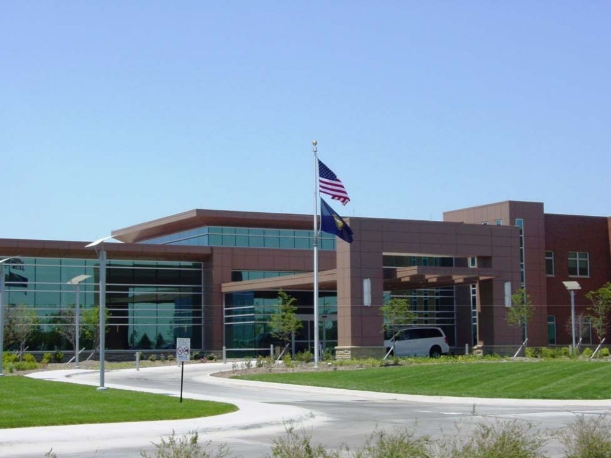 Modern glass-and-brick building with an American flag and lawn in front