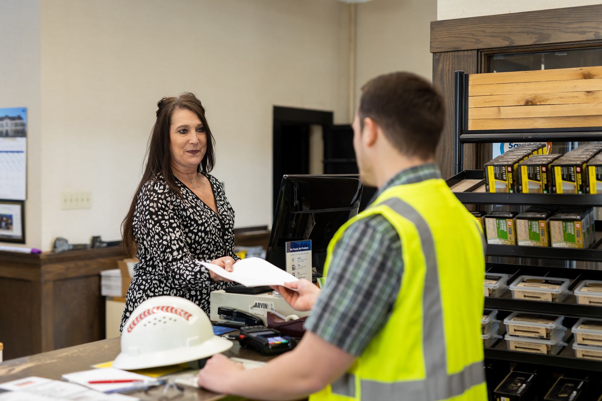 Store clerk handing a paper to a worker in a reflective safety vest near a counter