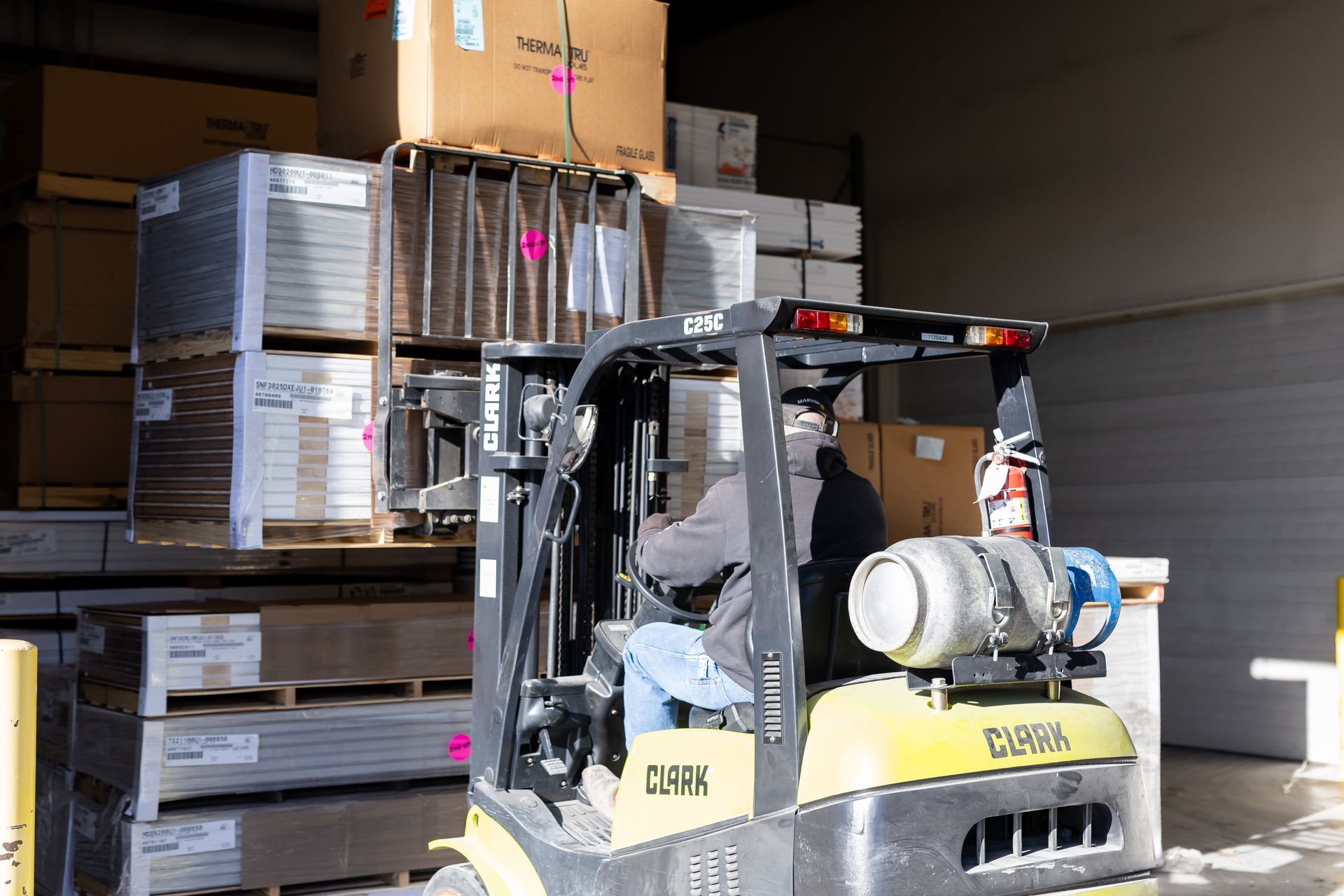 Forklift loading stacked cardboard boxes on pallets inside a warehouse