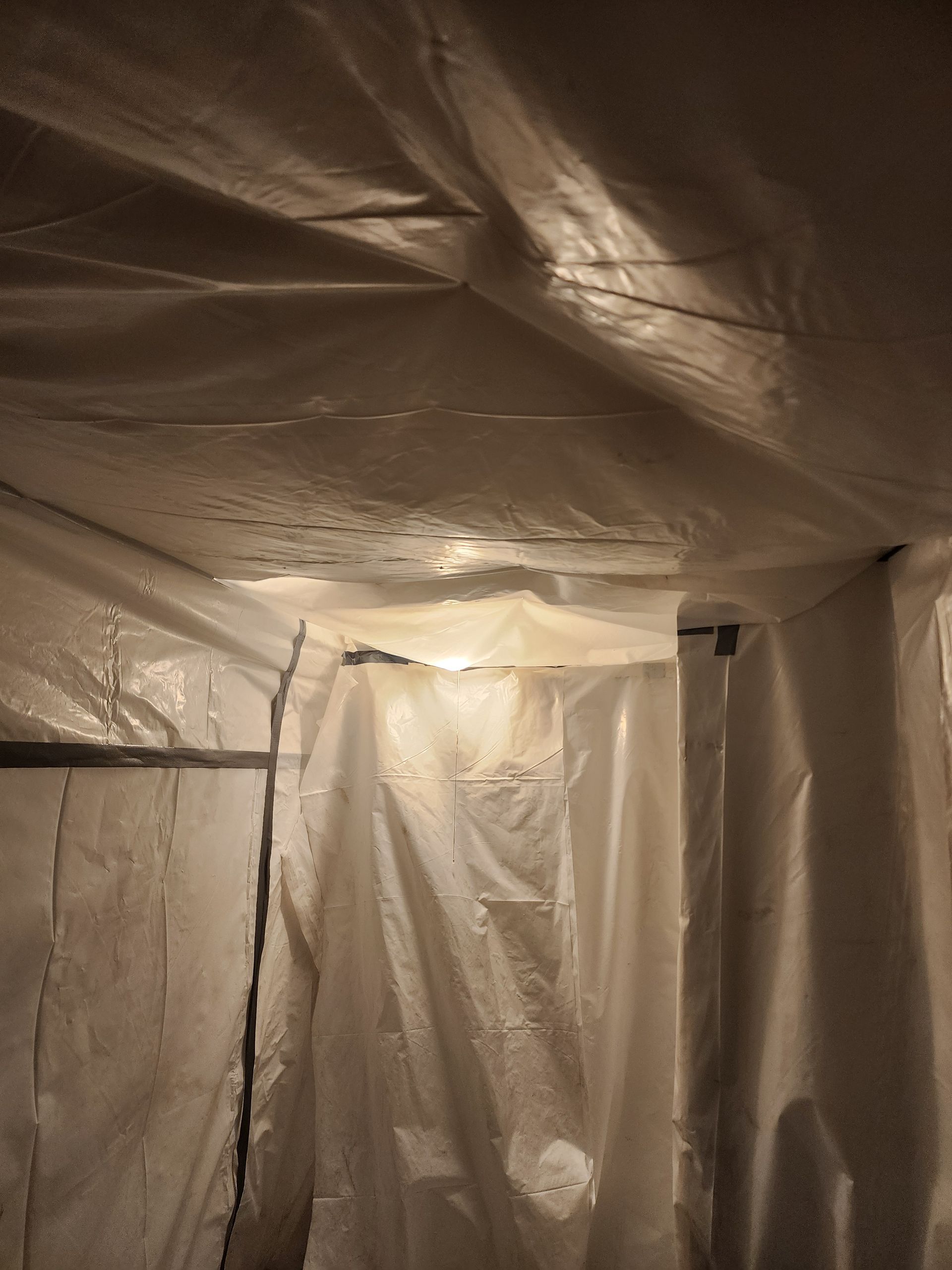 Interior view of a room with plastic sheeting on walls and ceiling; condensation present.