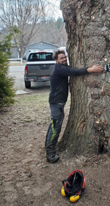 Tree Service expert Z-Man is leaning against a tree trunk in Teton Valley Idaho