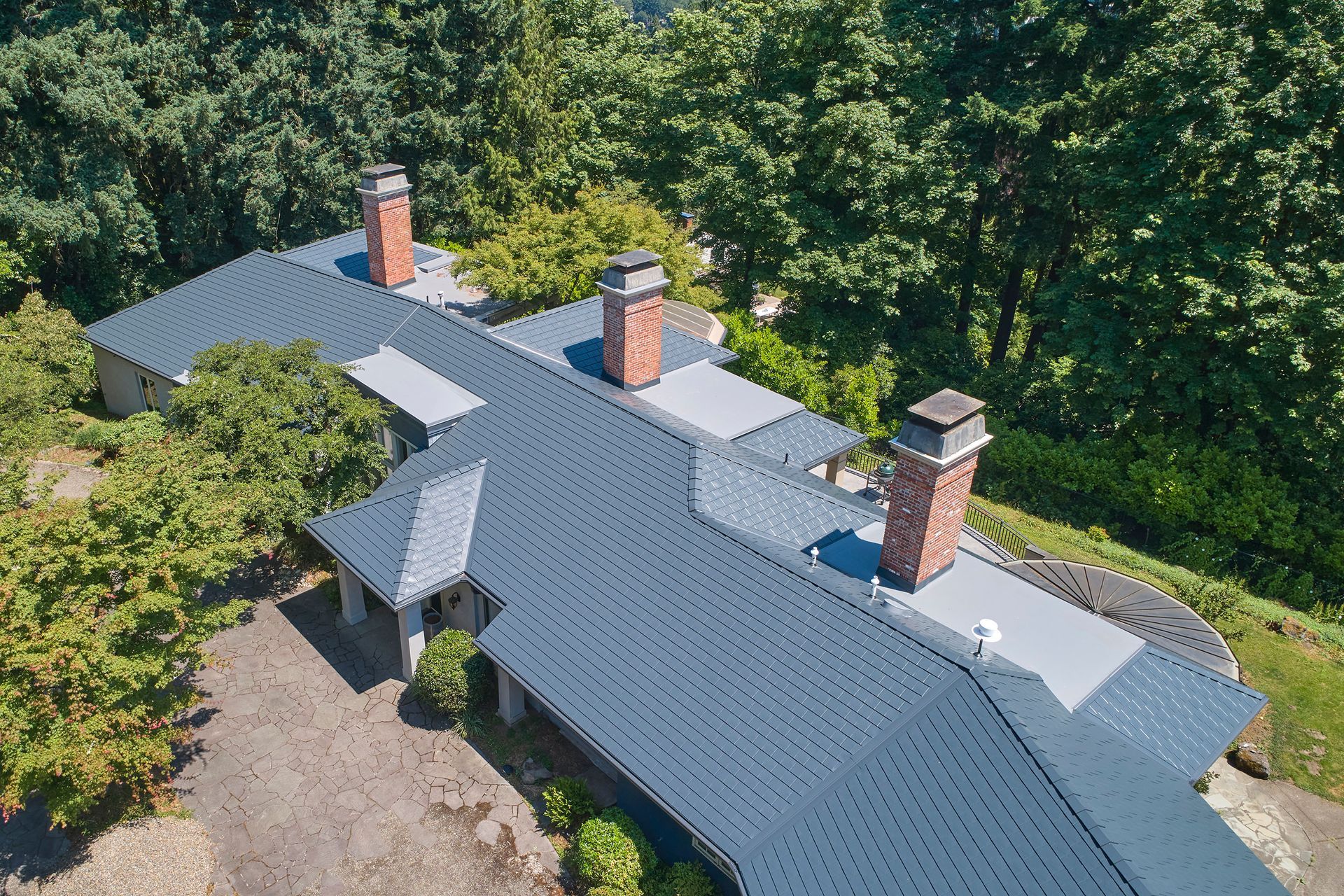 Bird’s-eye view of expansive Interlock aluminum slate roofing in deep charcoal across a custom-built Portland OR home in Dunthorpe. High-quality metal shingles are precision-aligned to endure harsh Pacific Northwest weather conditions.