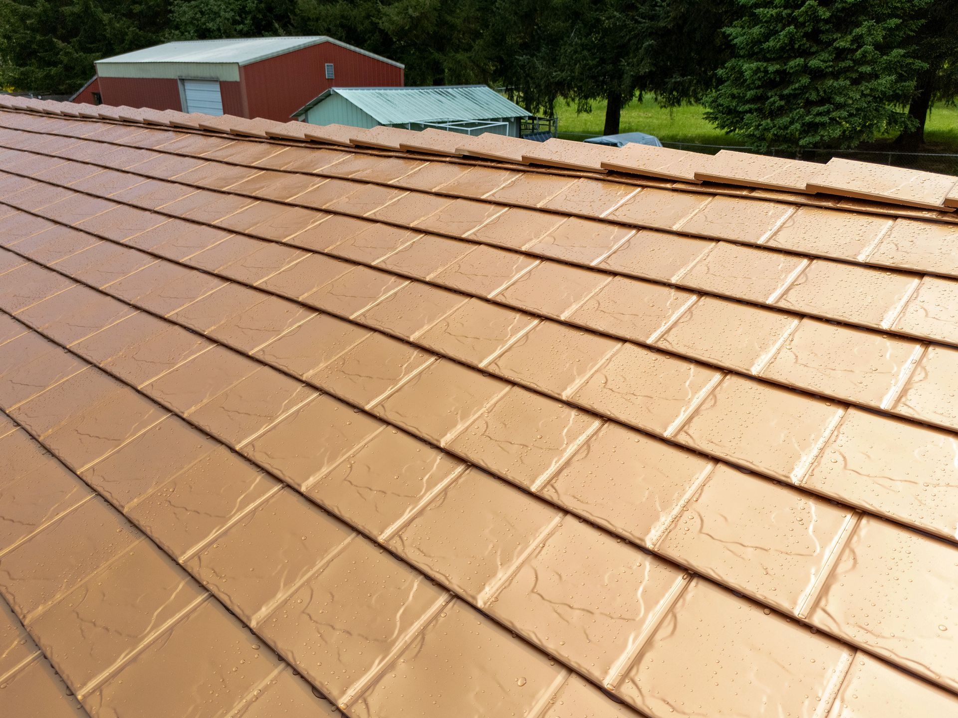 Angled view of wet Copper Penny Interlock aluminum roofing tiles after rainfall in Castle Rock, WA. Installed by Interlock Metal Roofing, the close-up reveals superior panel locking, rust-resistant coating, and fade-proof color perfect for the Pacific Northwest’s rainy climate.
