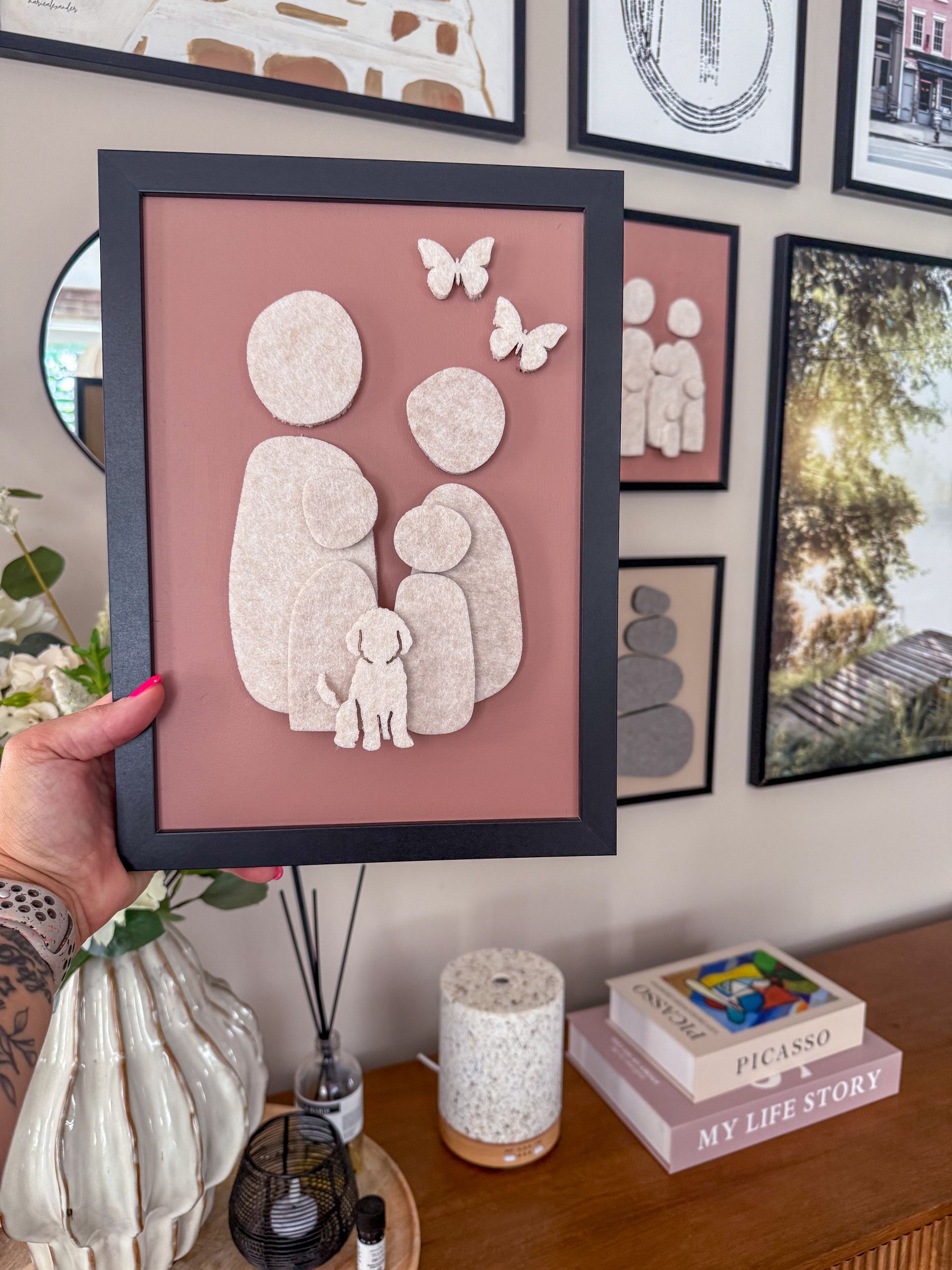 Handgemaakt familieportret van vilt in neutrale kleuren, ingelijst in hout – unieke wanddecoratie met silhouetten van gezinsleden.