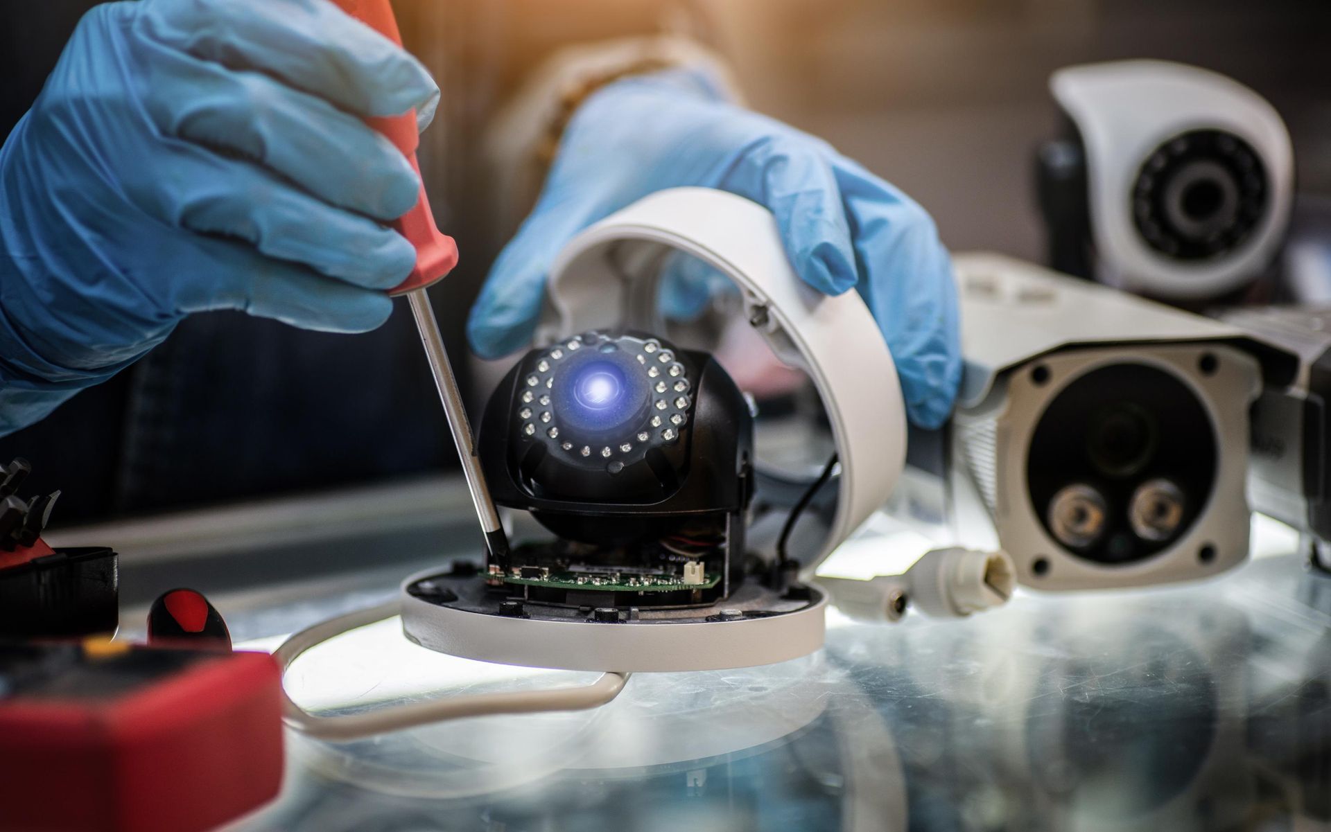 A person is fixing a security camera with a screwdriver.