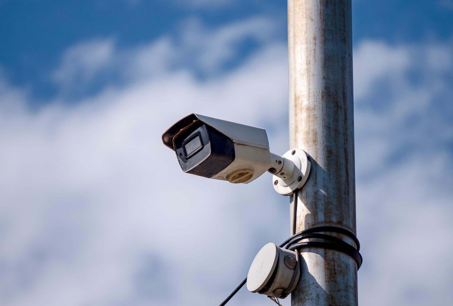 A security camera is sitting on top of a metal pole.