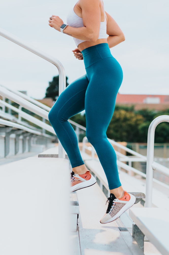 A woman in blue leggings is walking up stairs.