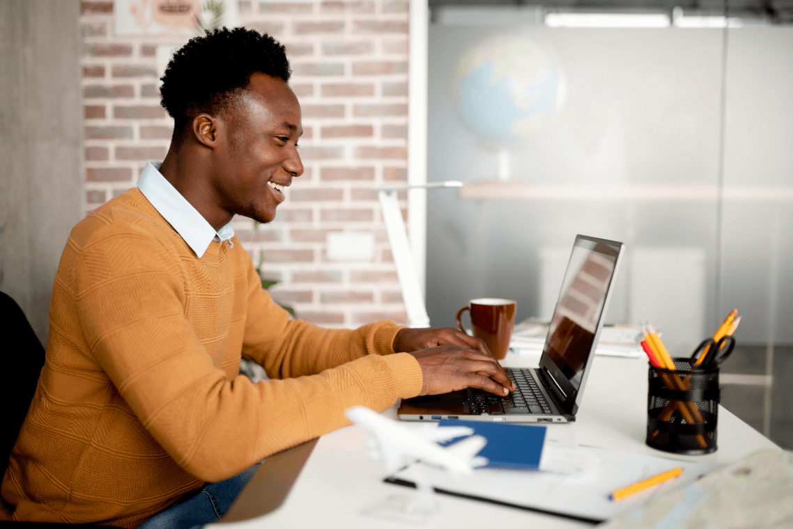 A man is sitting at a desk using a laptop computer.