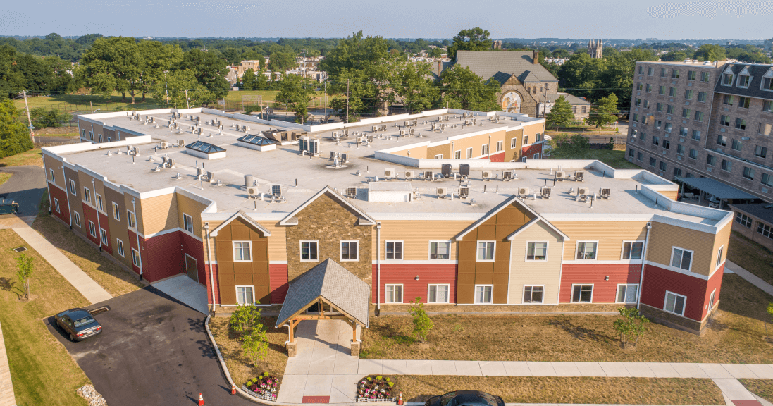 An aerial view of a large apartment building with cars parked in front of it.