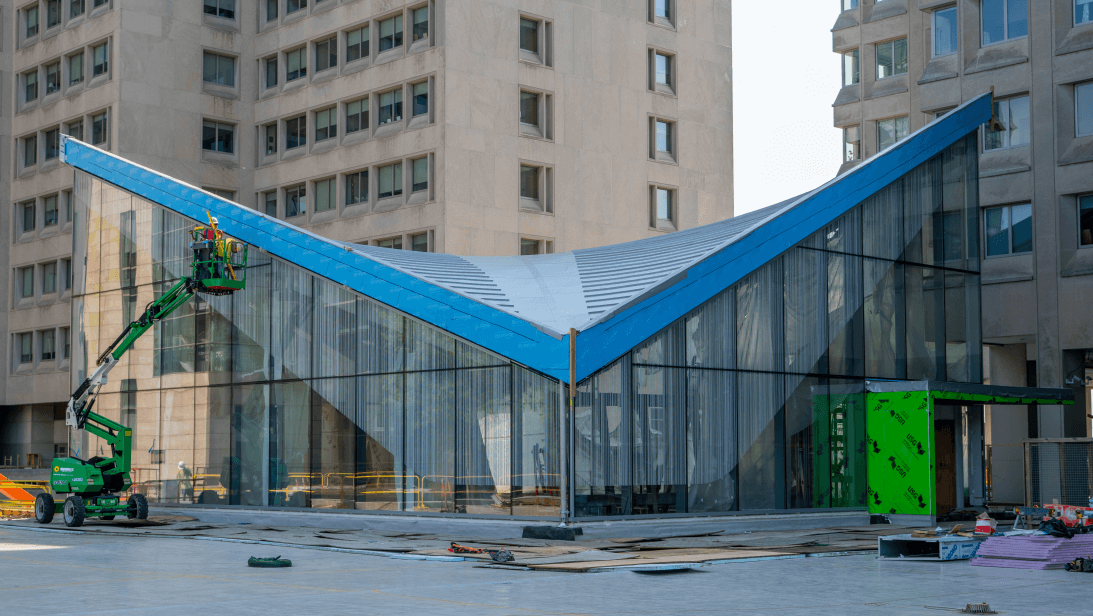 A building with a blue roof is being built in a city.