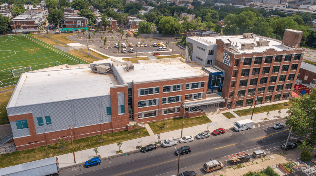 An aerial view of a large brick building with cars parked in front of it.