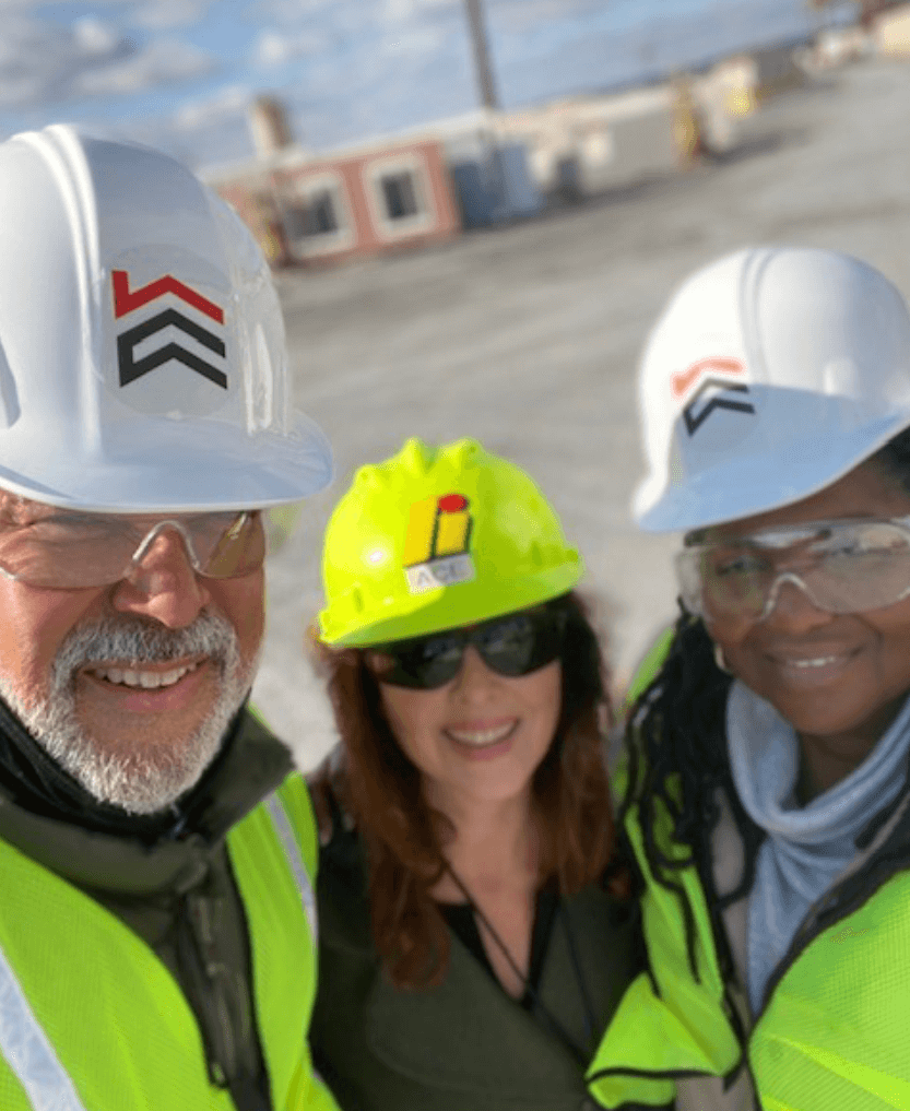 Three people wearing hard hats and safety vests pose for a picture