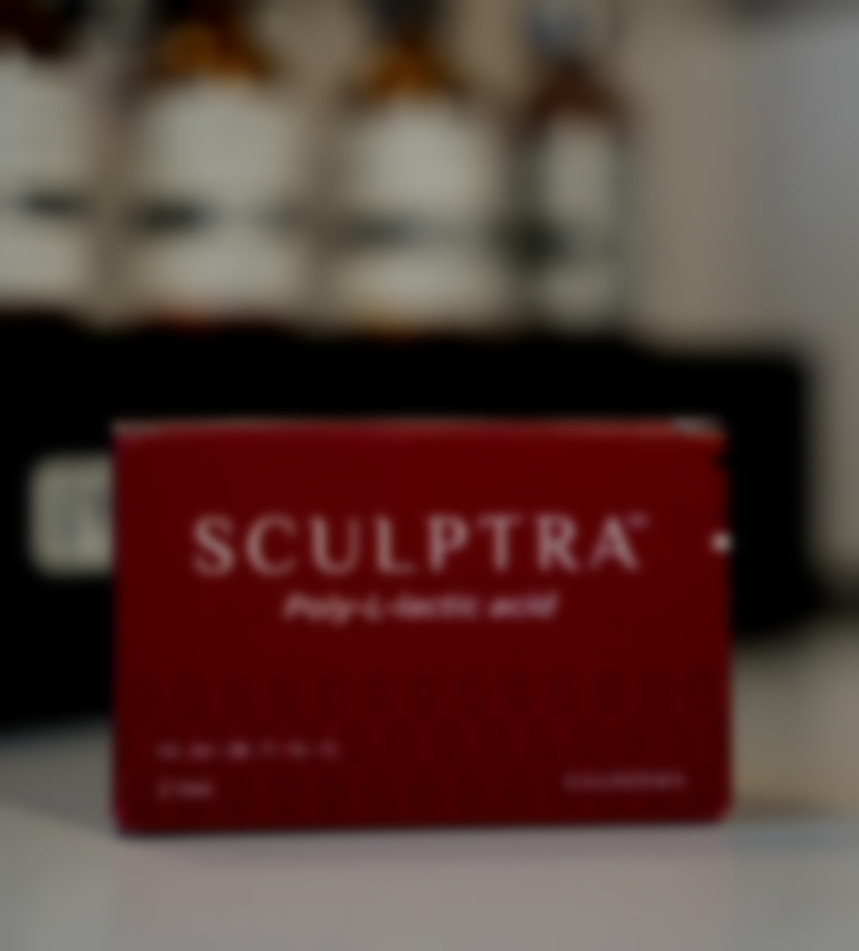 Red box of Sculptra, Poly-L-lactic acid, on a white surface with blurred bottles in the background.