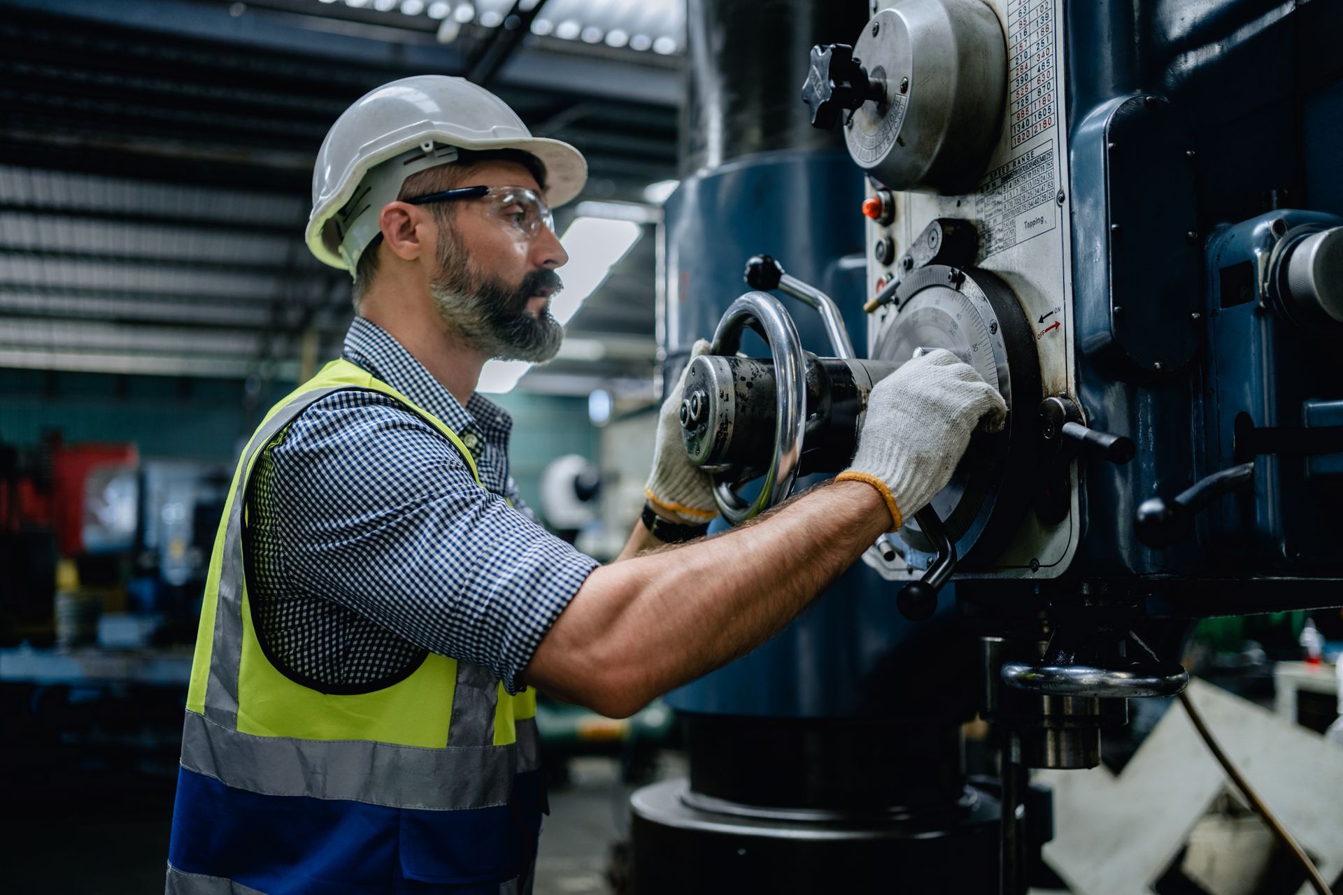 A mechanic in a safety uniform wearing glasses is performing a machinery service