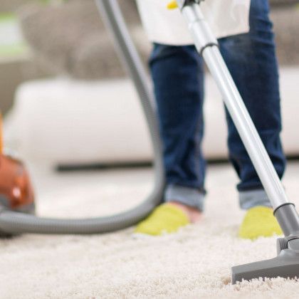 A person is using a vacuum cleaner to clean a carpet.