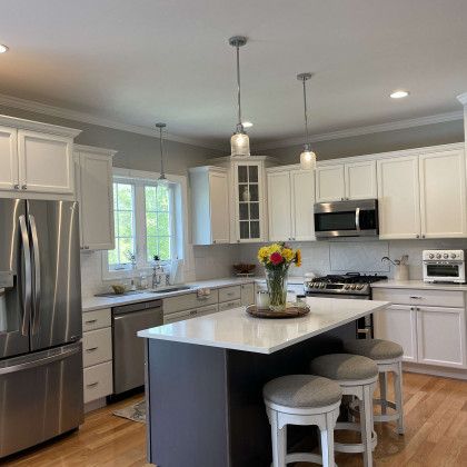 A kitchen with white cabinets , stainless steel appliances , and a large island.