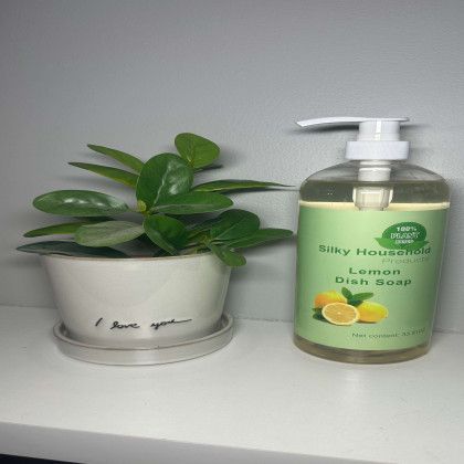 A bottle of silky household lemon dish soap next to a potted plant.