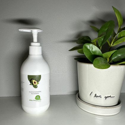 A bottle of soap is sitting next to a potted plant.