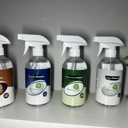 A row of spray bottles sitting on top of a white shelf.