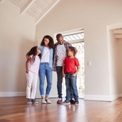 A family is standing in an empty room in their new home.
