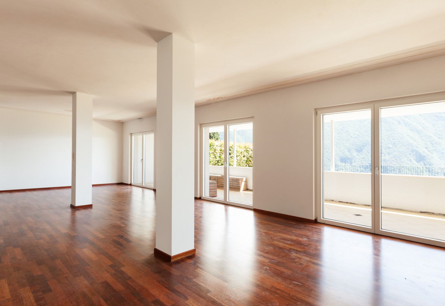 A large empty room with hardwood floors and lots of windows.
