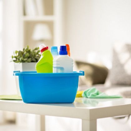 A blue bowl filled with cleaning supplies is sitting on a table.