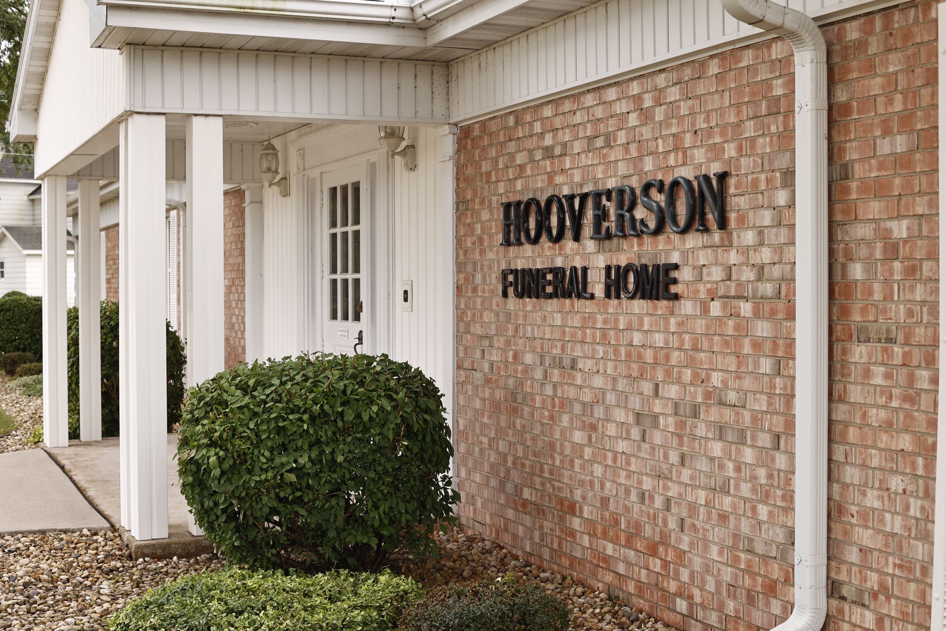 Hoverson Funeral Home brick building with sign above door, with green shrubbery in front.