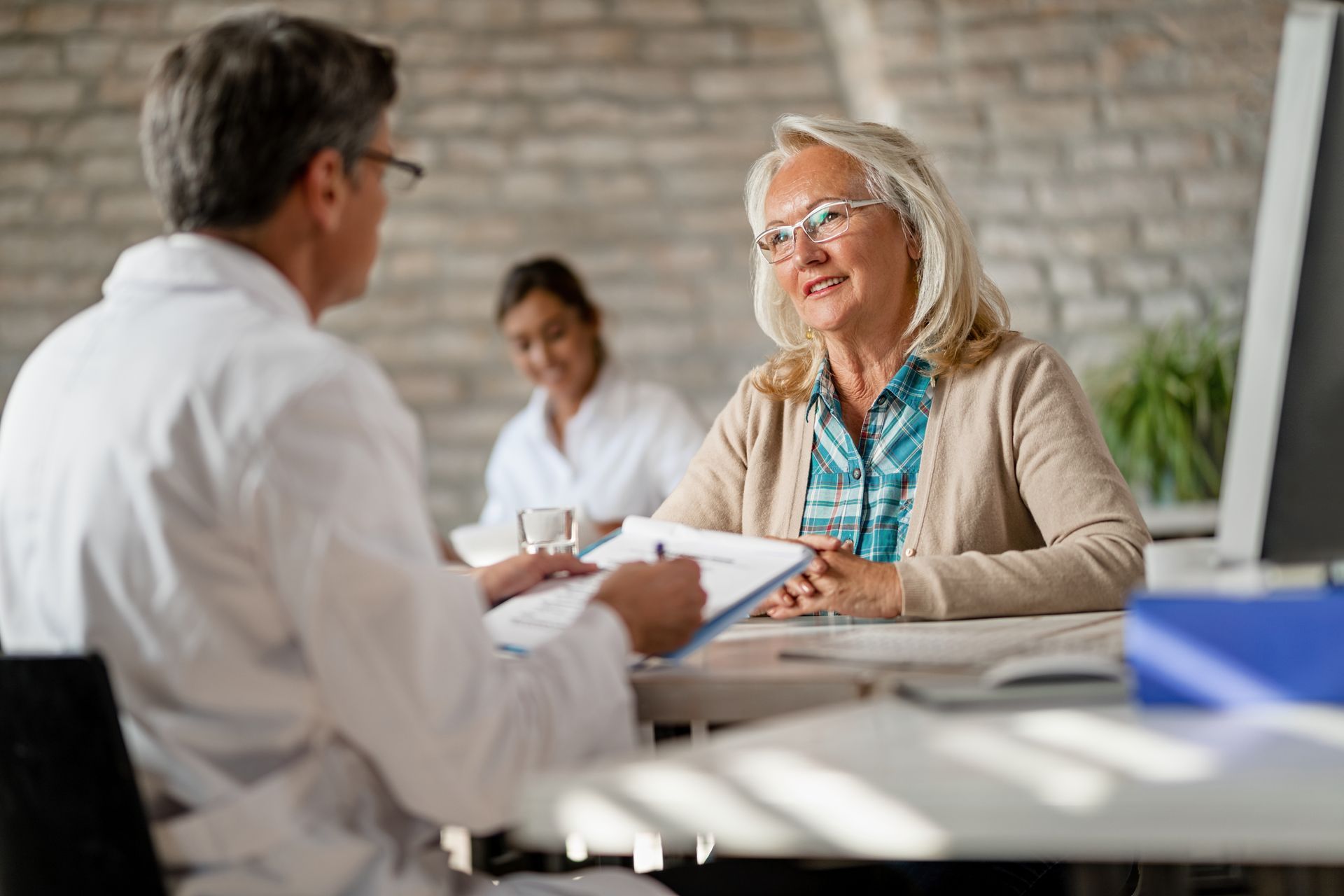 Two people in a bright office, discussing documents across a table