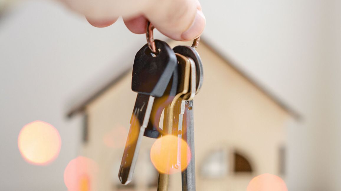 a person is holding a bunch of keys in front of a model house .
